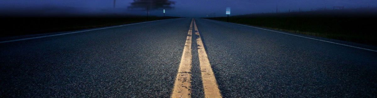 Black road at night with a yellow line